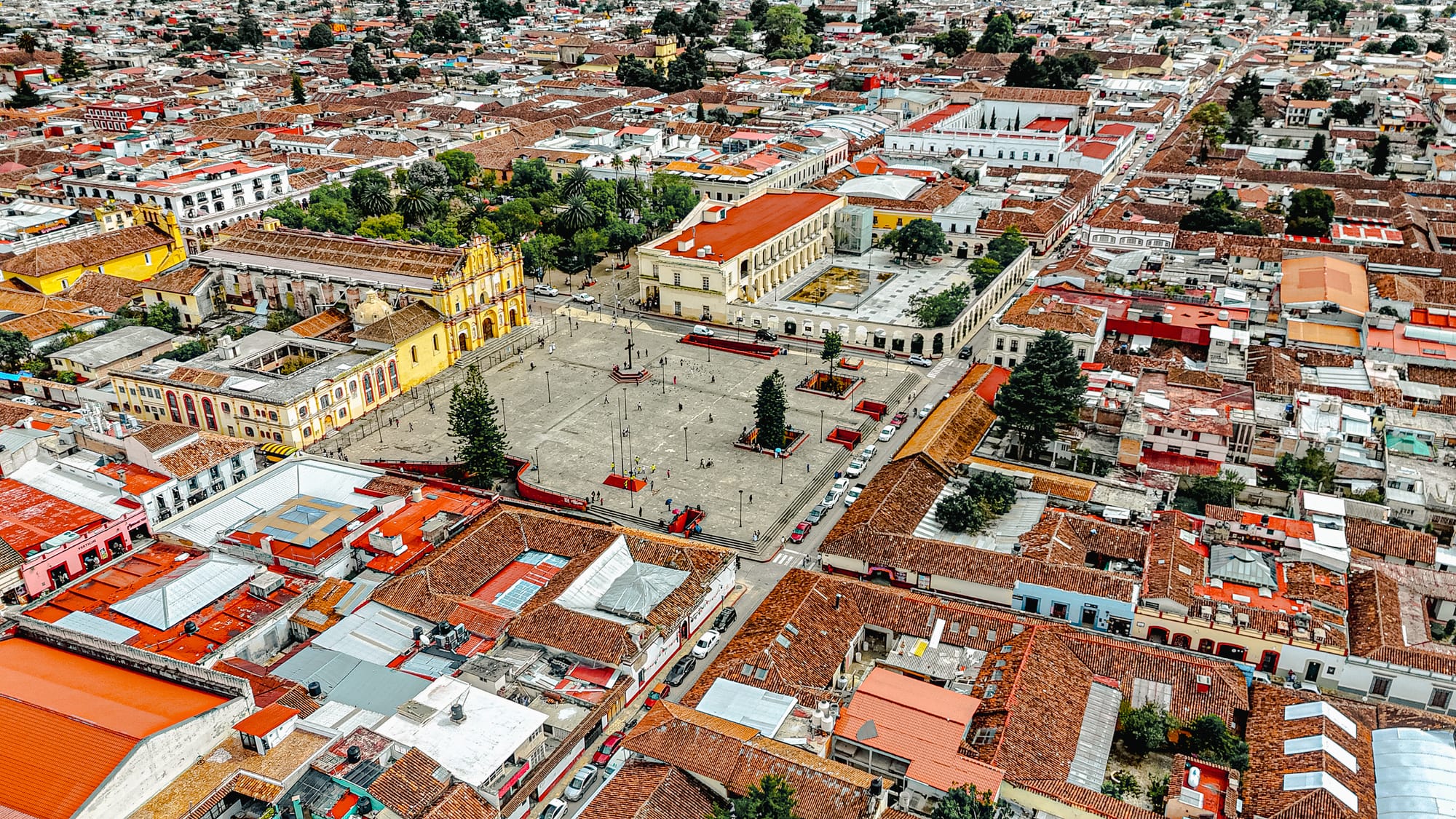 Aerial view of San Cristóbal de las Casas showing Plaza 31 de Marzo, Catedral de San Cristóbal Mártir, and the surrounding historic center with red-tiled roofs in Chiapas, Mexico