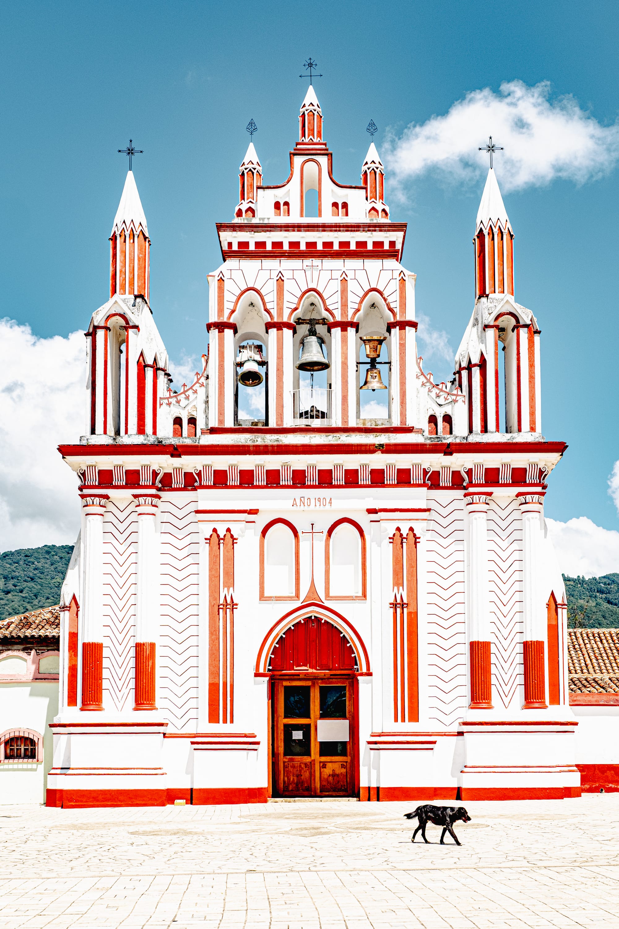 Front view of Templo de Nuestra Señora de la Asunción in San Cristóbal de las Casas, Chiapas, Mexico, showing its red and white neo-Gothic façade, bell towers, central entrance, and the year 1904 above the doorway
