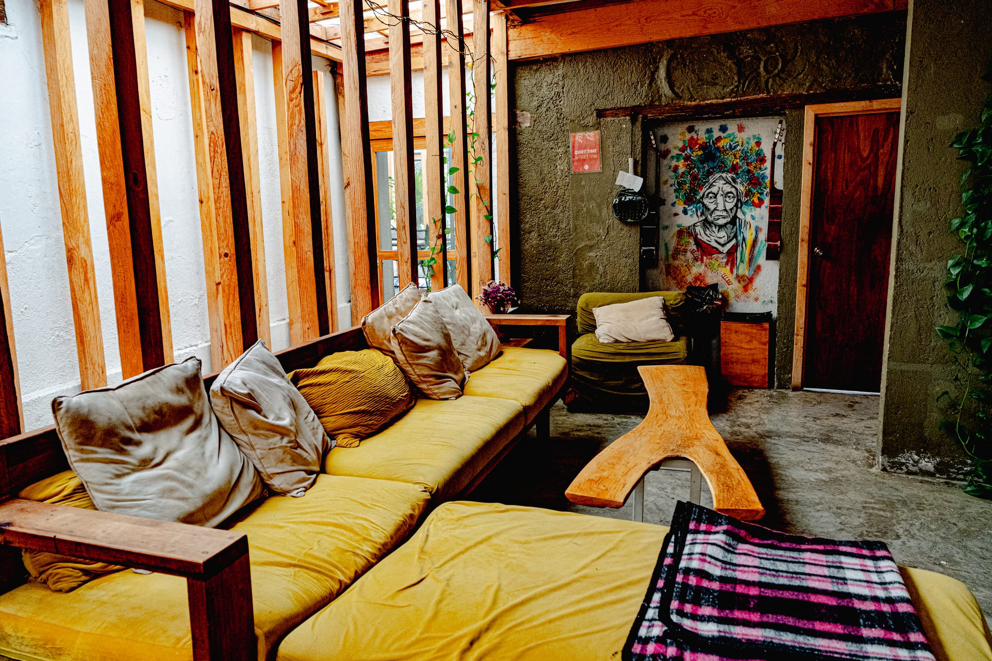 Indoor lounge area at Co404 coliving in San Cristóbal de las Casas, featuring cushioned seating, wooden details, and colorful wall art