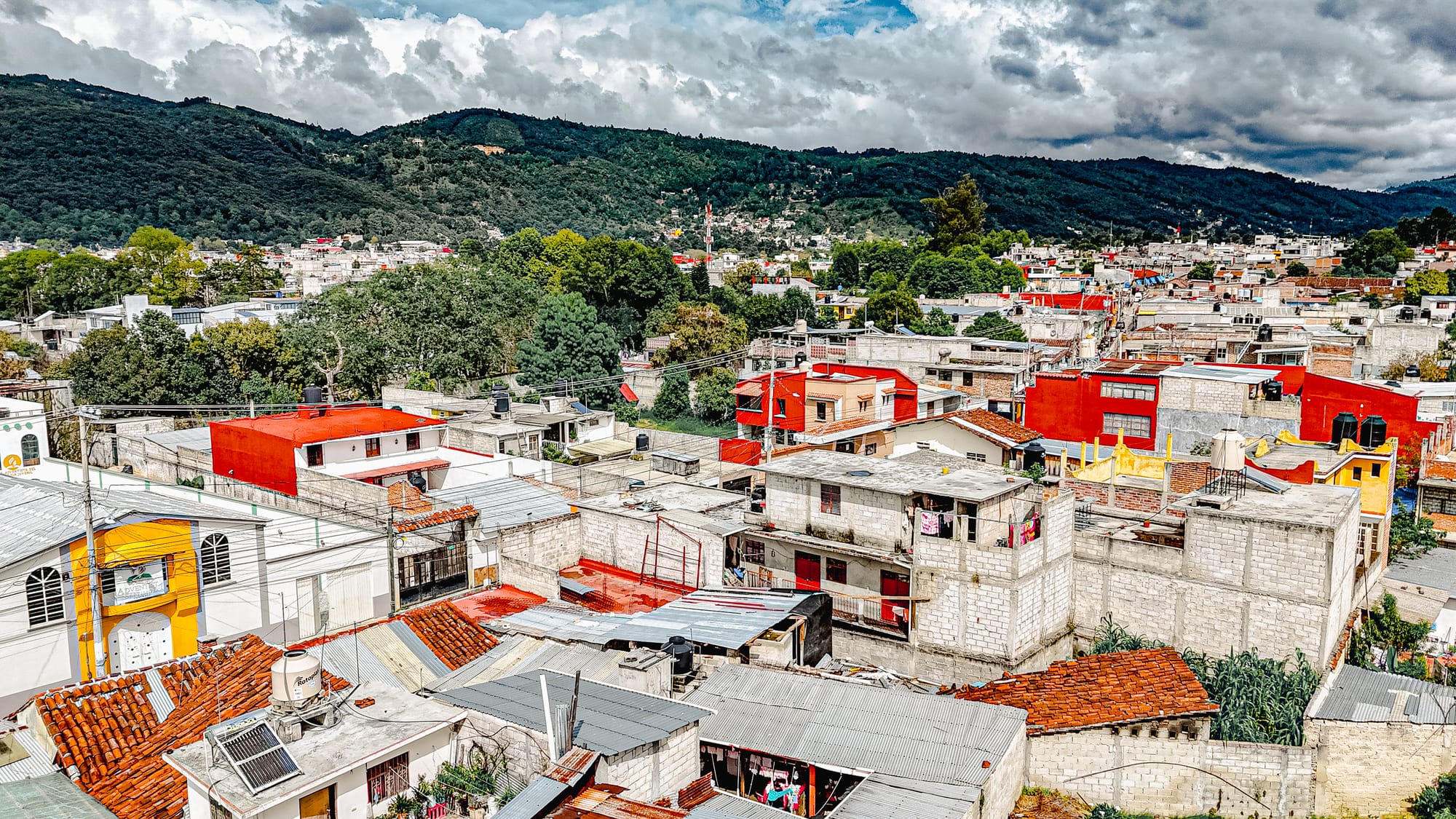 View of the surrounding neighborhood in San Cristóbal de las Casas, with colorful houses, rooftops, and the green hills that border the city