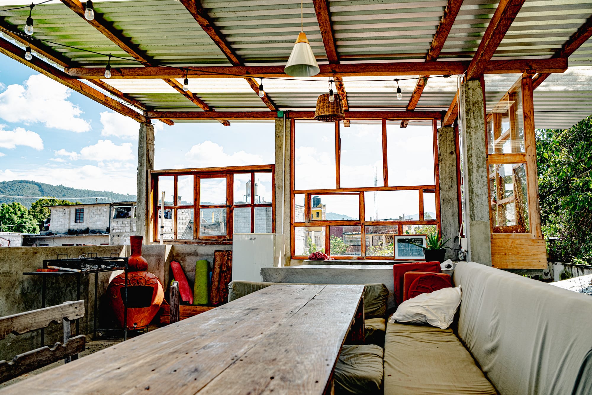 Rooftop common area at Co404 coliving in San Cristóbal de las Casas, with rustic wooden tables, seating, and open views of the surrounding mountains