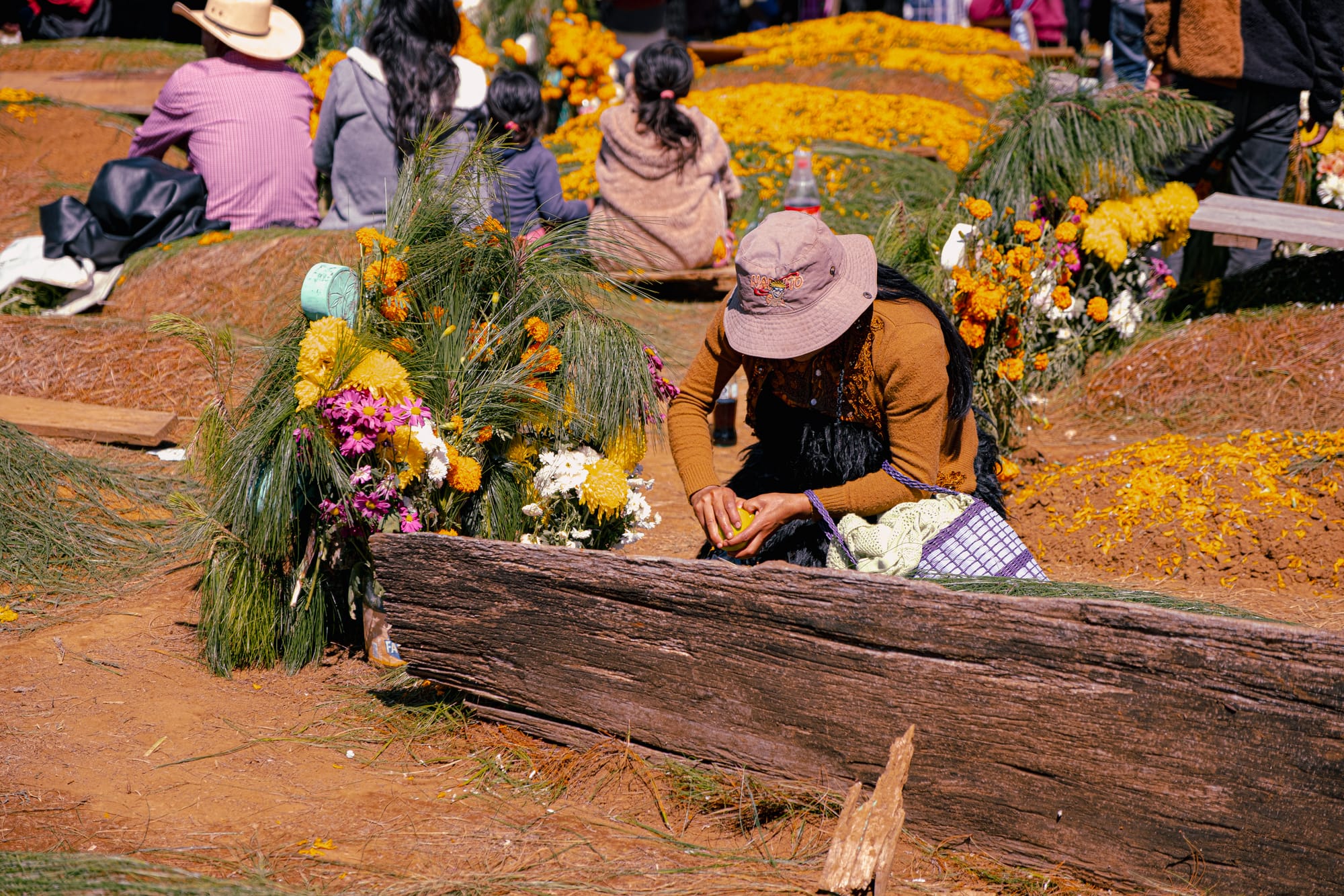 Digital nomad life in San Cristóbal de las Casas Mexico, Day of the Dead at Romerillo cemetery in Chiapas Highlands, indigenous woman preparing grave with flowers and offerings, intimate family remembrance during Día de los Muertos, spiritual cultural tradition near San Cristóbal, Day of the Dead experience in southern Mexico