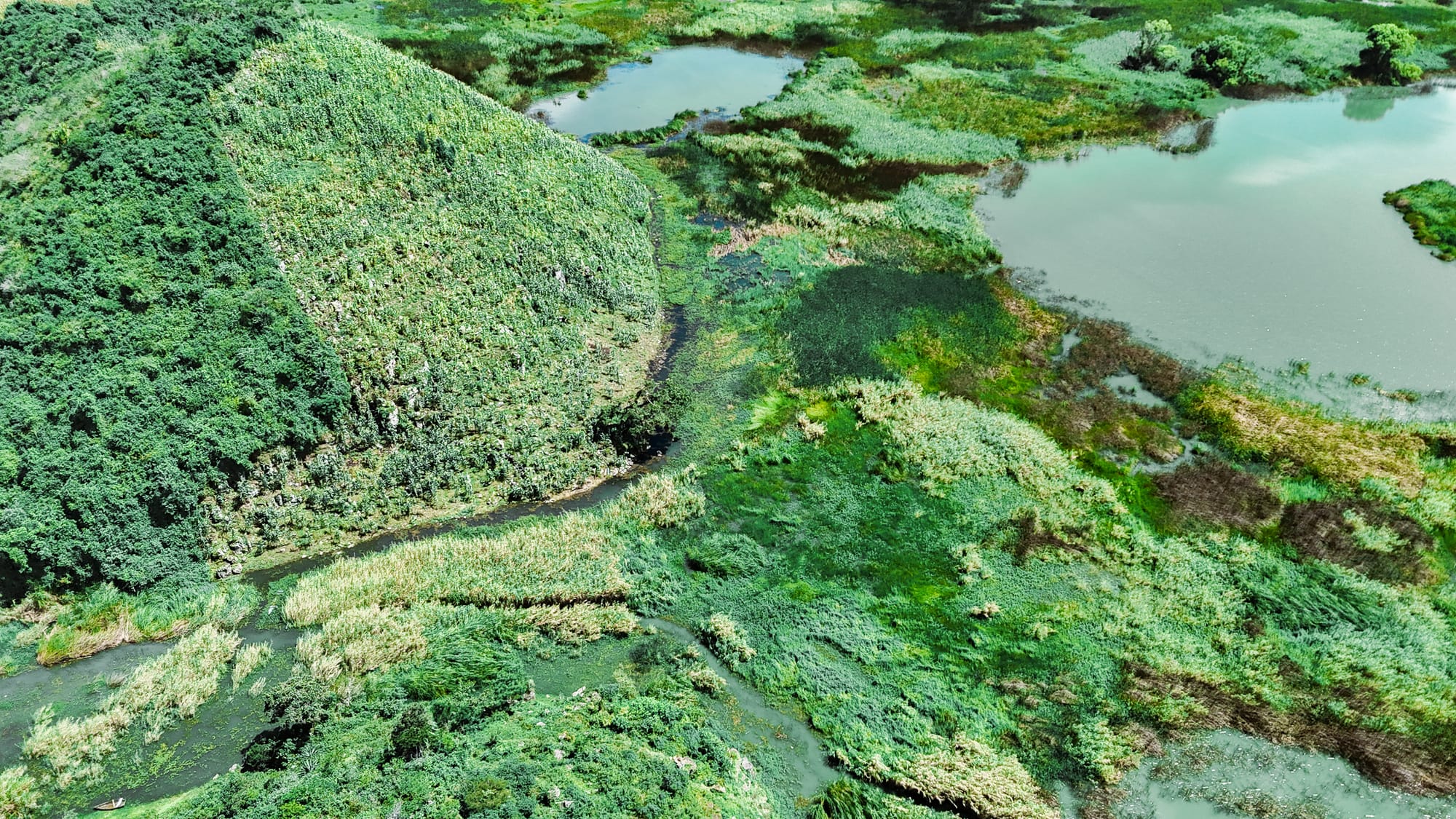 Aerial view of the wetlands and green hills surrounding Montebello Lakes in Chiapas, showing turquoise water channels, dense vegetation, and the layered landscape near the Guatemala border