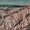 Expansive view of Cappadocia’s Red Valley, featuring dramatic pink and white rock ridges carved by erosion, with distant hills and scattered clouds under a muted sky