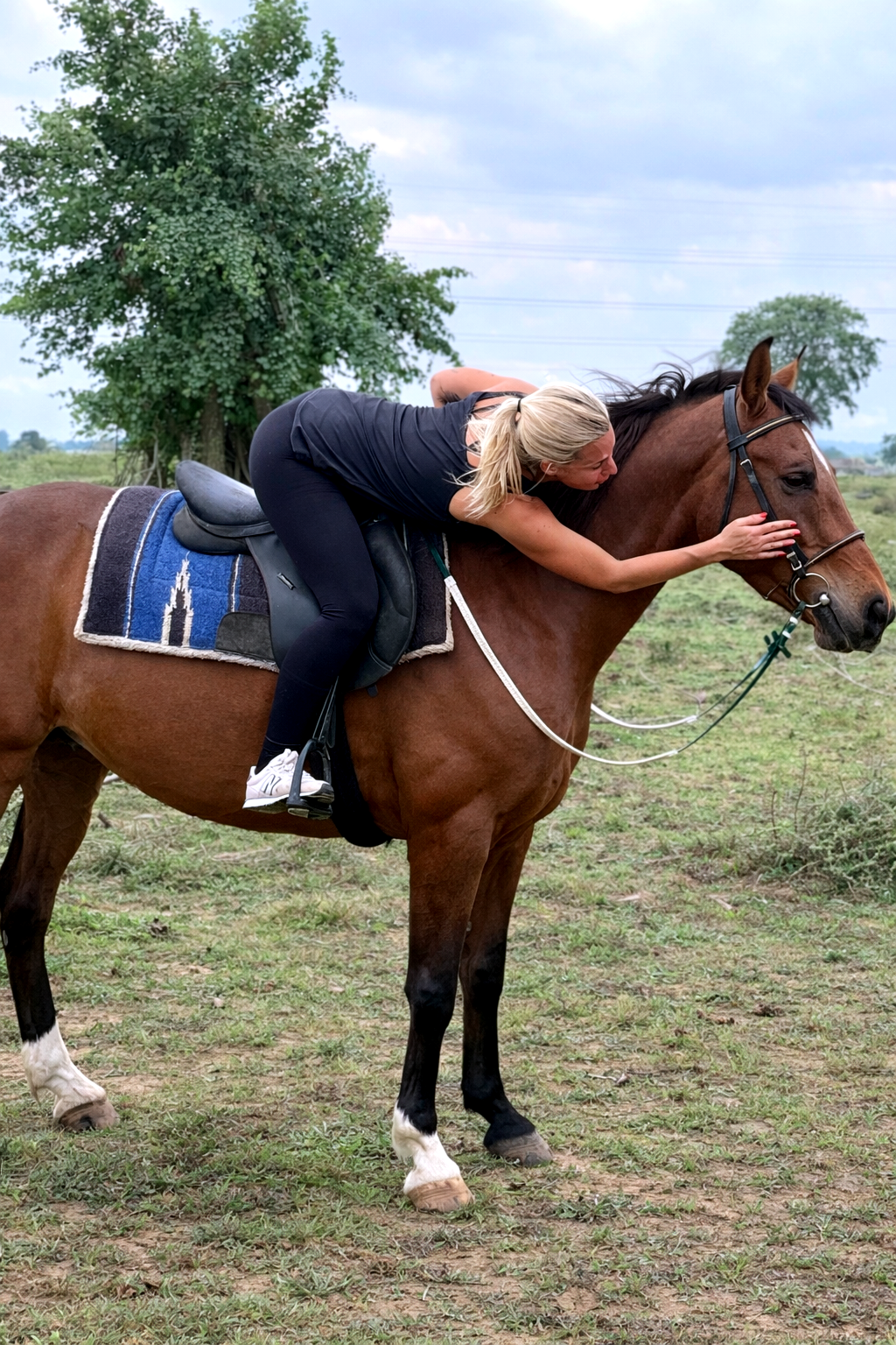 Rider resting forward in a calm moment of trust with a standing horse in an open field at Vonfidel Ranch.
