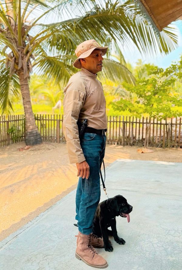 A handler stands in a relaxed working posture beside a young working dog at Vonfidel Ranch, demonstrating calm, relationship-based leadership as defined in The Fidelity Method™.