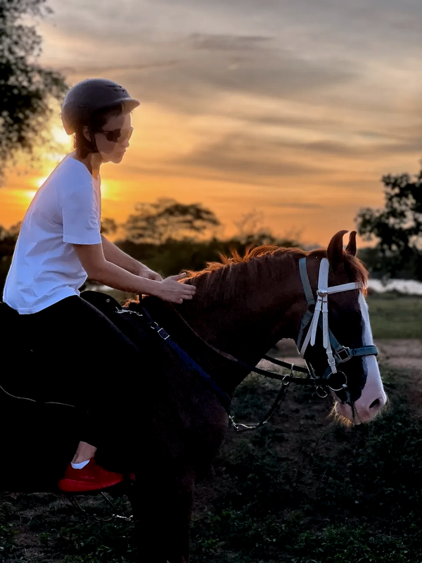 Horse and rider crossing the lakeside grasslands at sunrise in the Eastern Province of Sri Lanka — signature Vonfidel Ranch experience.