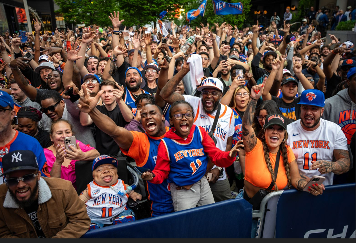 Diverse crowd of NYC residents cheering at a Knicks watch party on the street