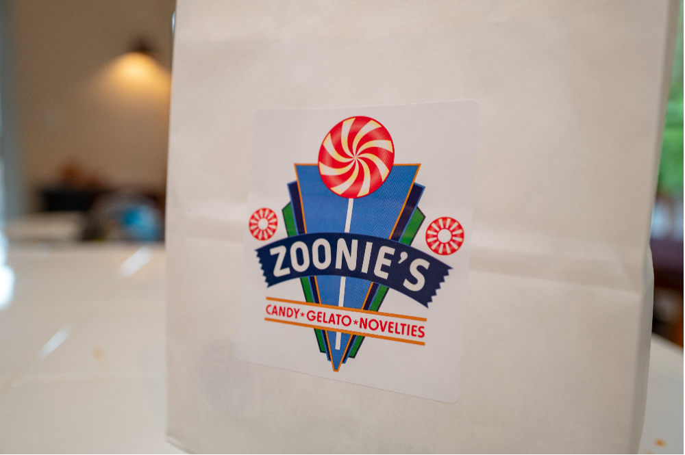 Closeup on the Zoonie’s logo with a peppermint lollypop on a white paper bag.
