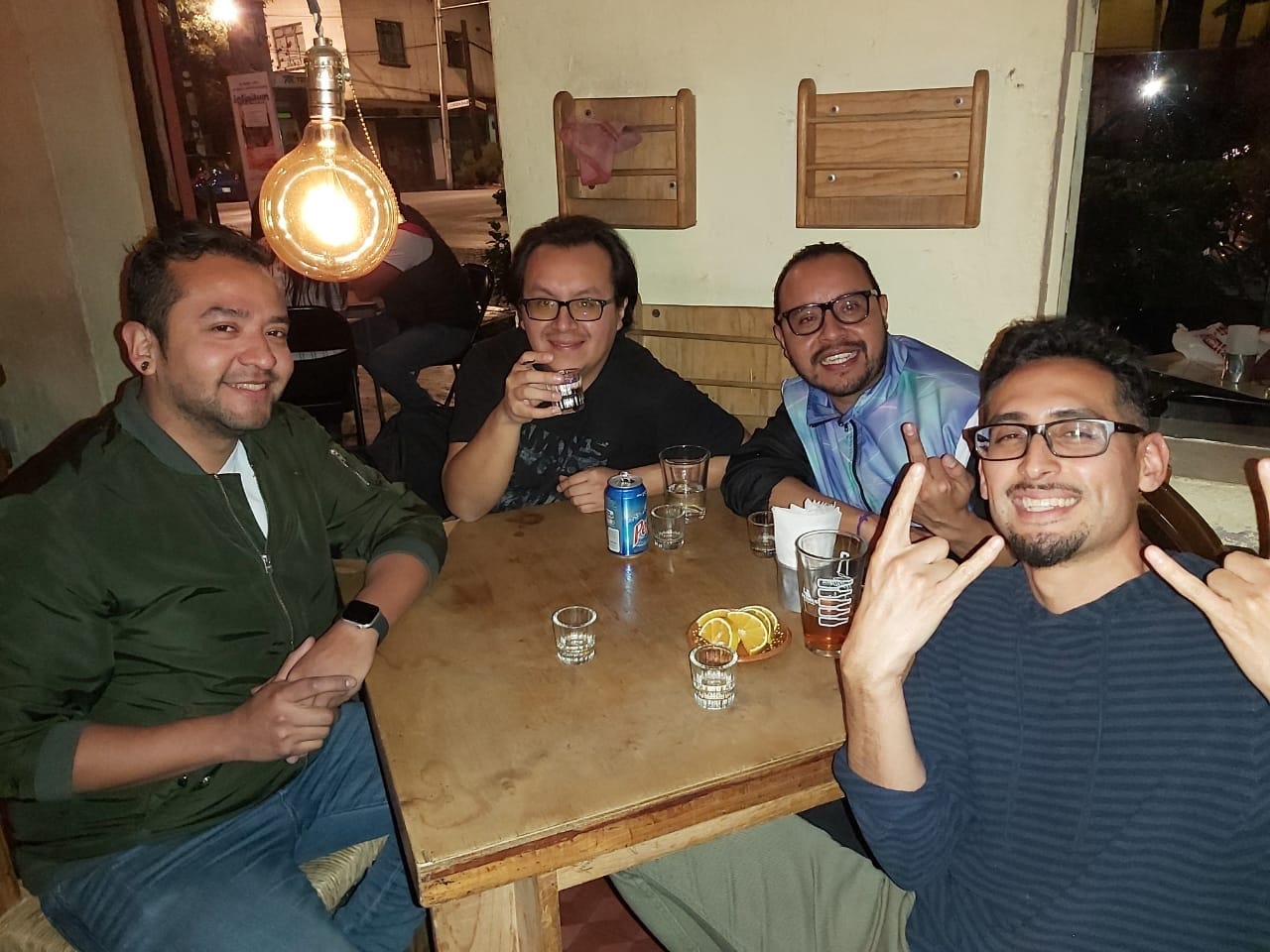 Four smiling men sitting at a table in a restaurant at night.