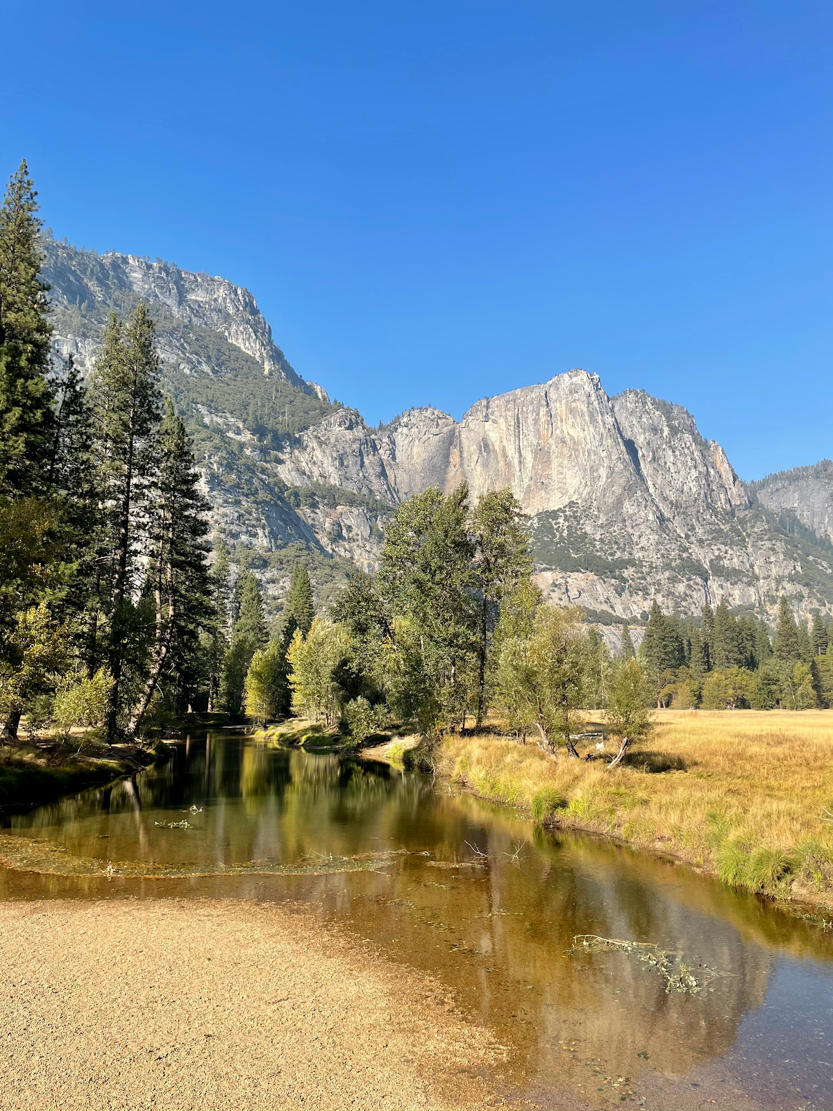 A very shallow creek in an open area with cliffs in the background.