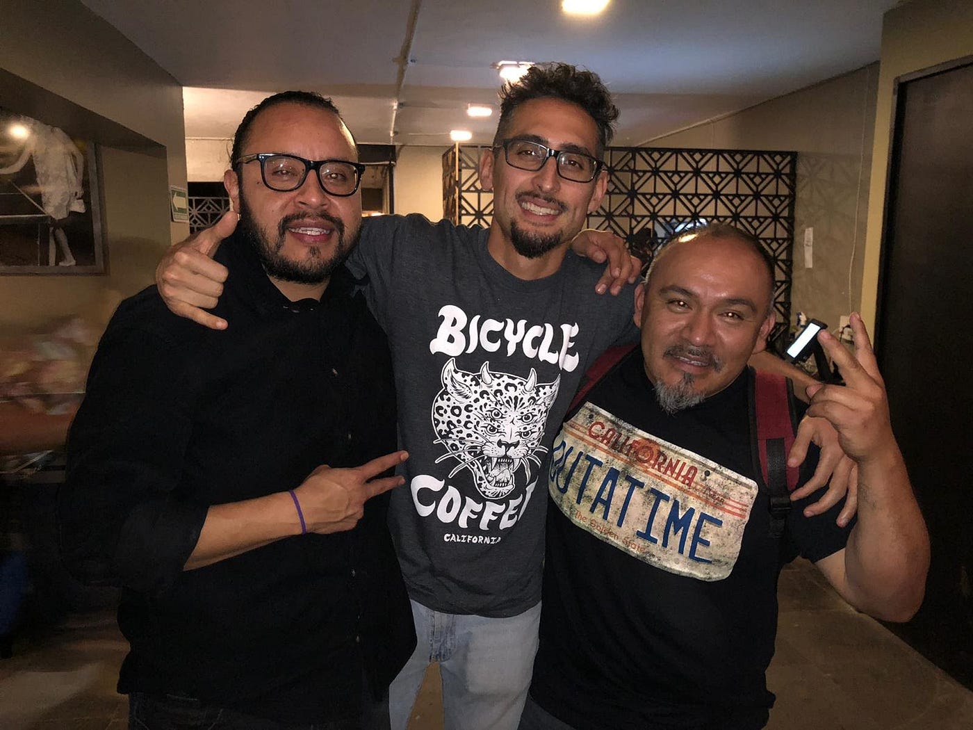 Three smiling men posing in a lobby.