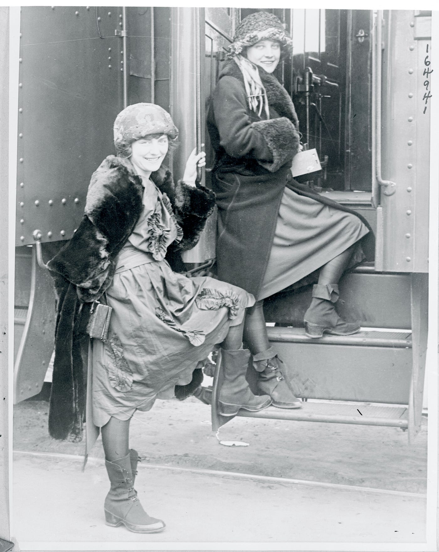 Vintage photo of two women posing next to a train.