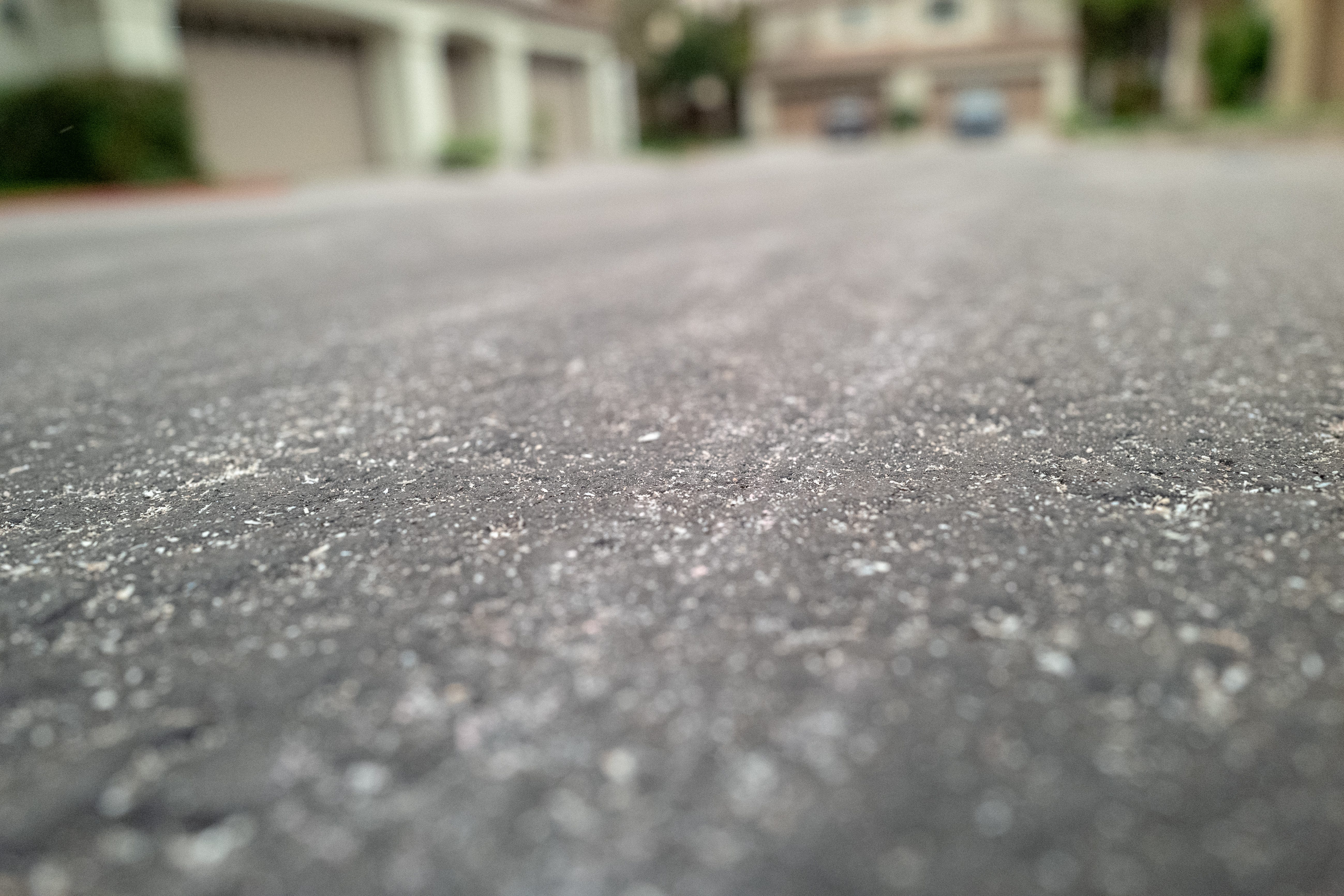 Closeup of particles of ash on an asphalt road. The field of focus is very narrow, creating a tilt-shift effect.