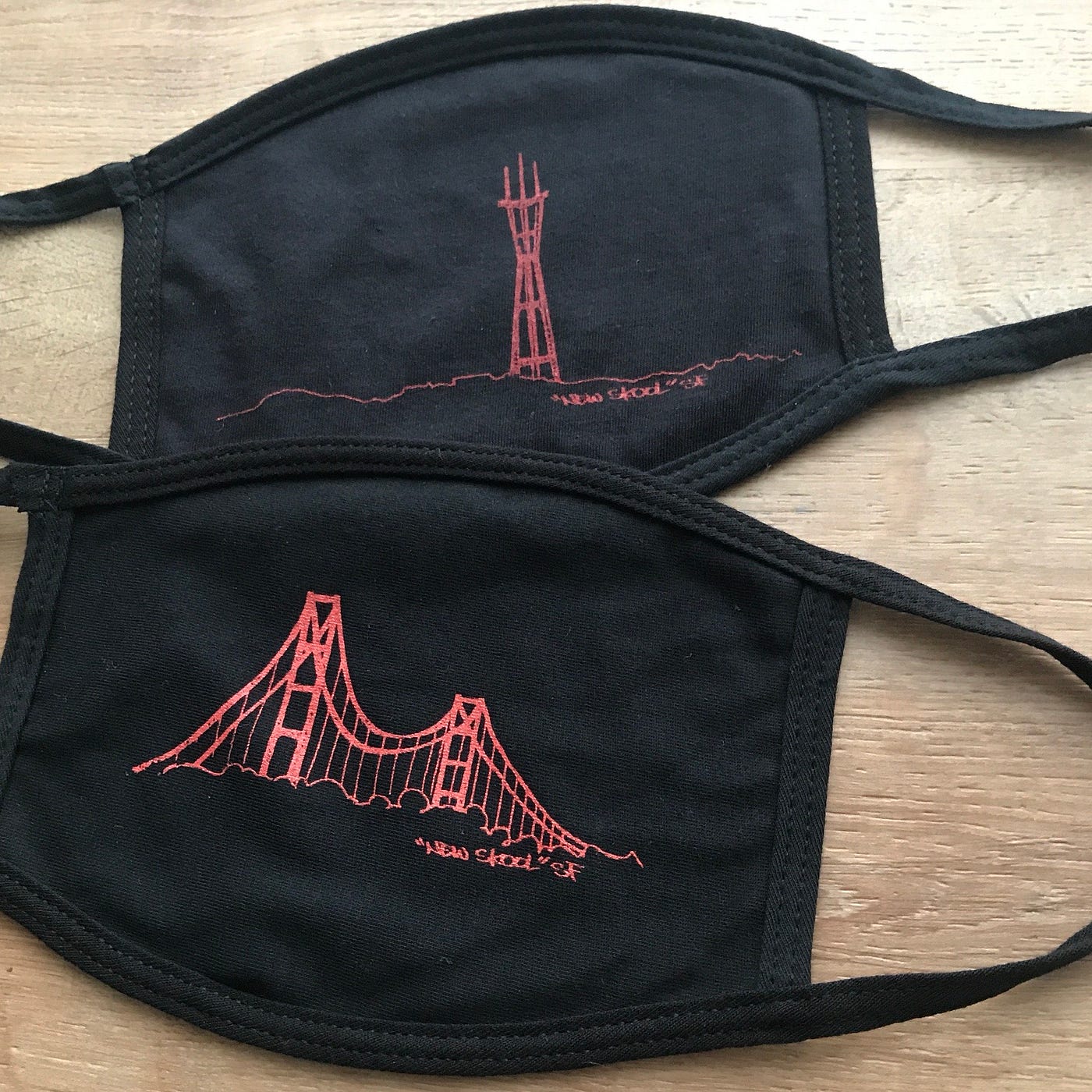 Two black masks, one with the Sutro Tower spray-painted on in red, and the other with the Golden Gate bridge.