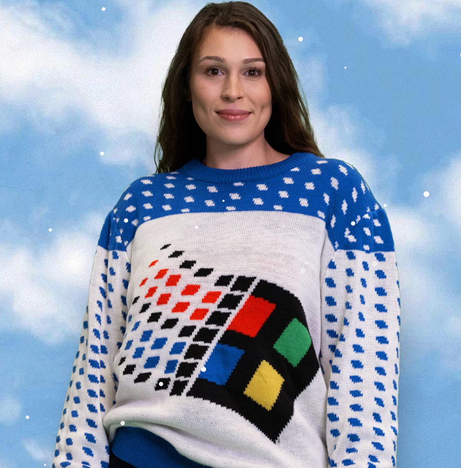 A long-haired, light-skinned person wearing a sweater with polka dots and the Windows 95 logo.