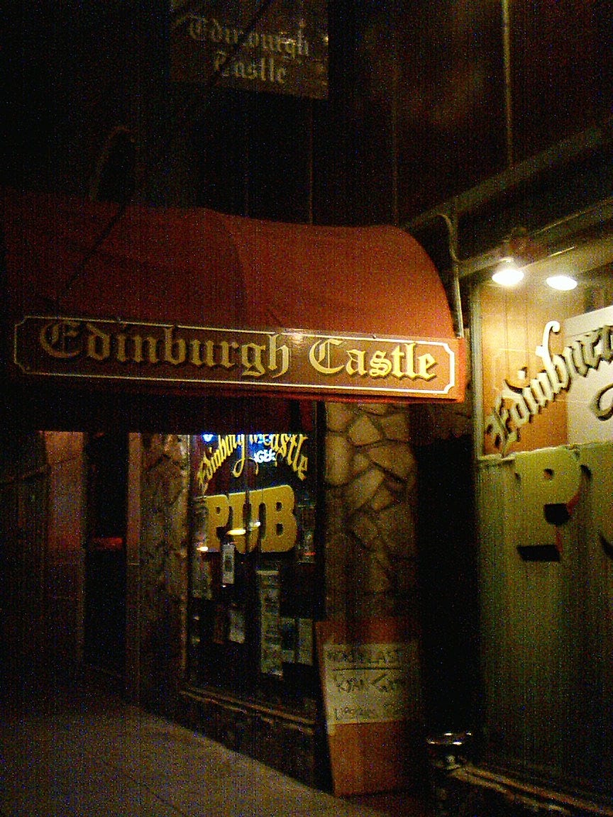 The exterior of a pub with a large red awning at night.