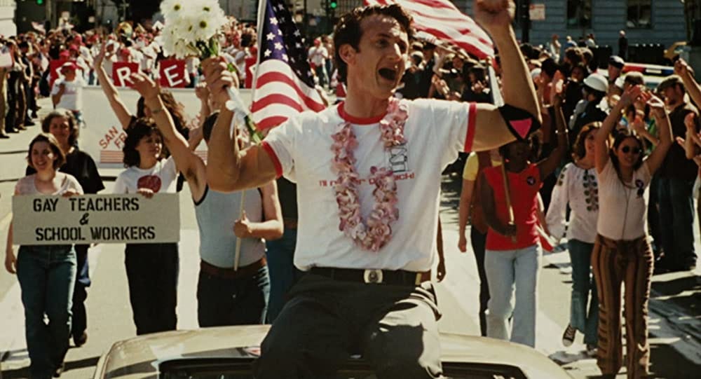 Harvey Milk (Sean Penn) cheering from the back of a convertible during a parade.