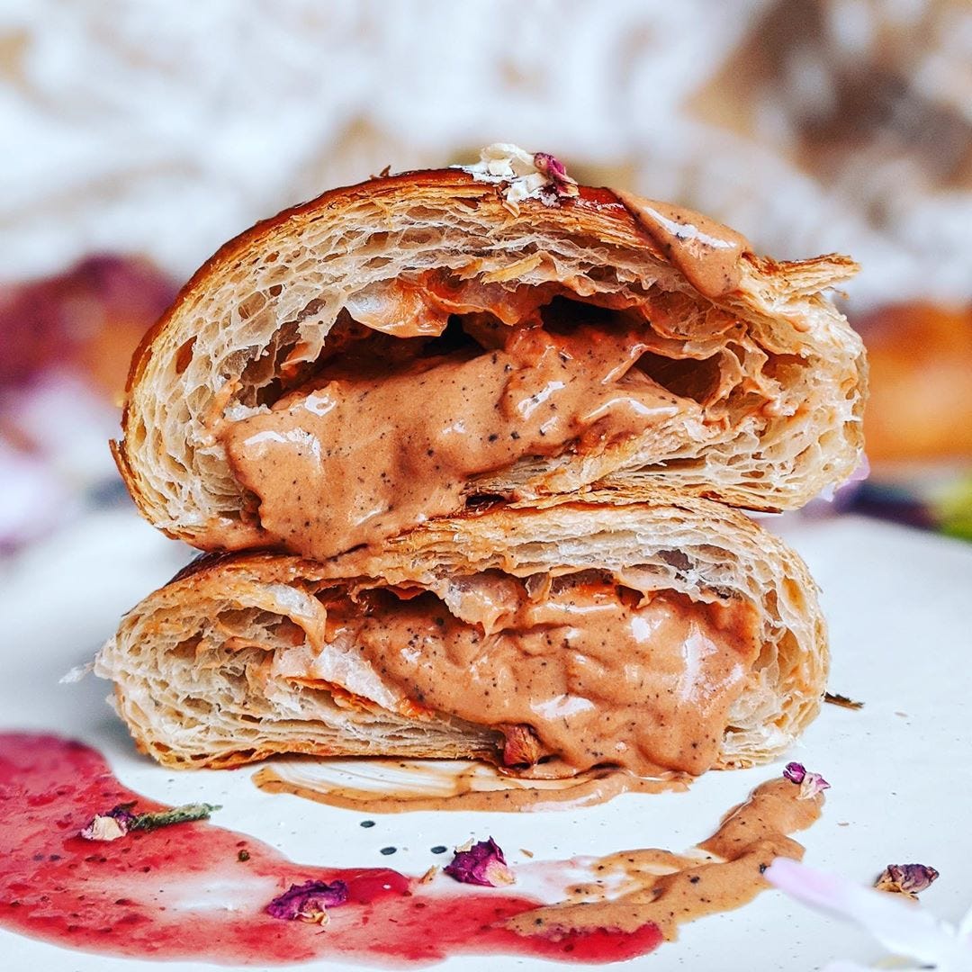 A halved croissant filled with a orangish/pinkish sauce.