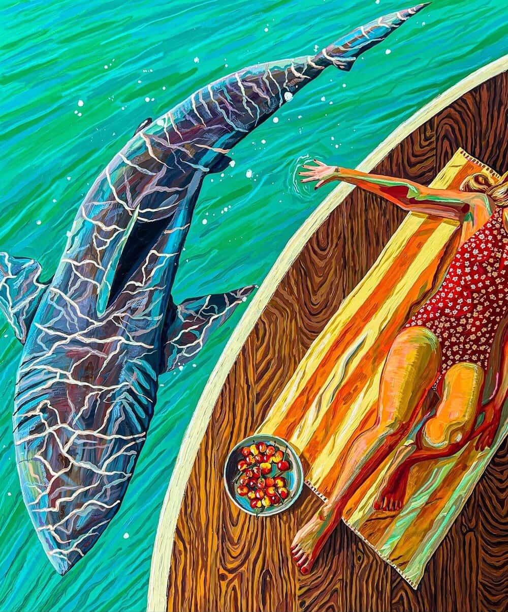 A woman lies on a deck beside bright green water as a large shark swims just below the surface nearby.