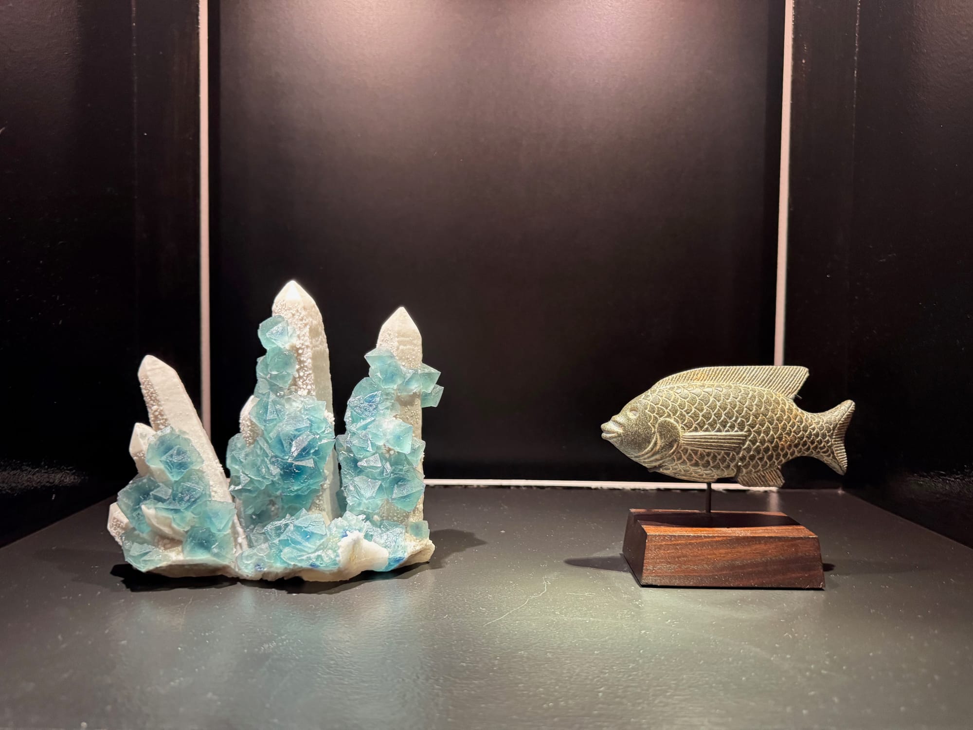 An Egyptian basalt cosmetic dish in the shape of a fish was shown with a quartz and blue fluorite cluster