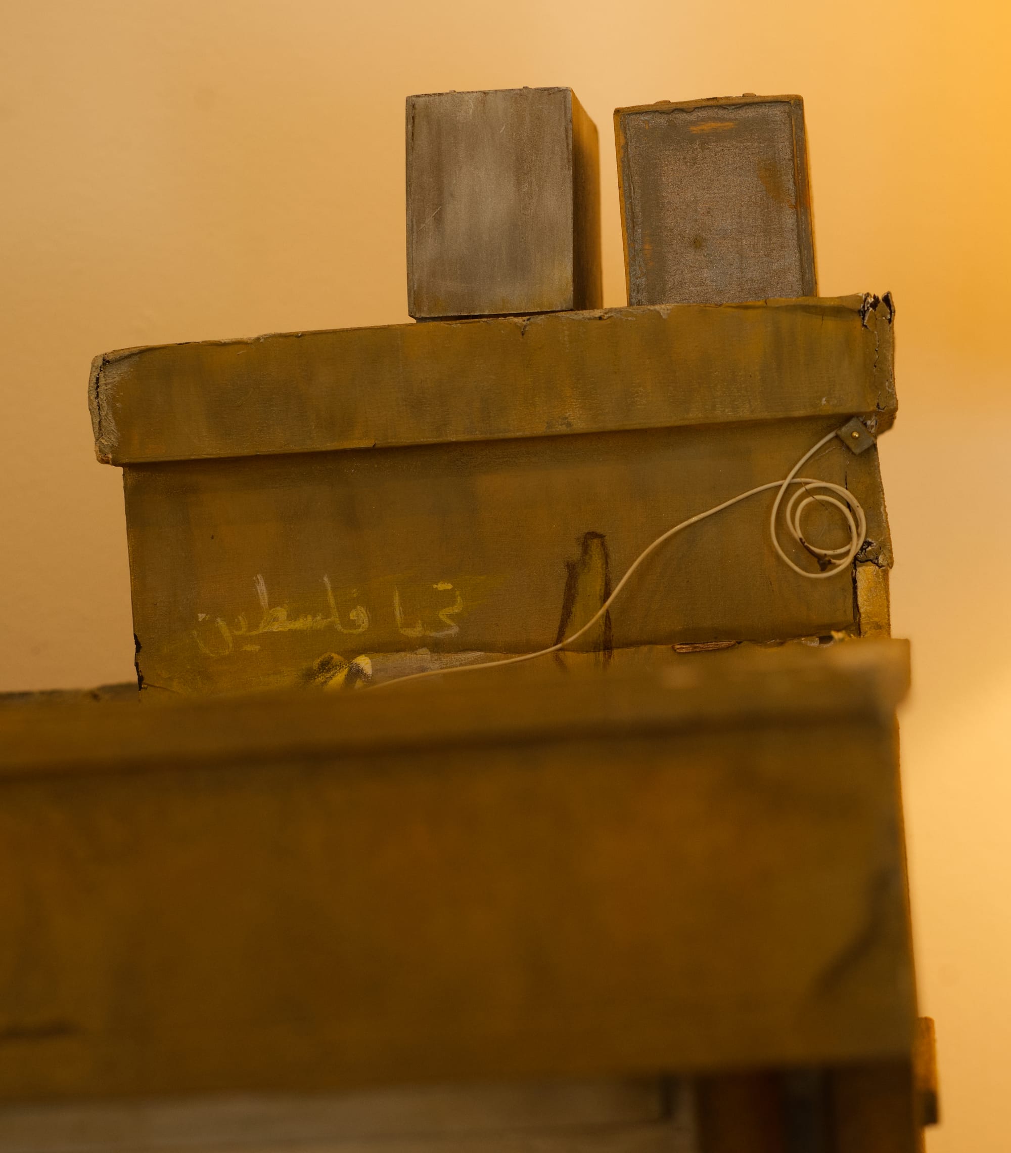 Close-up of a rooftop section of the model building, showing weathered walls, small structures, exposed wiring, and faint Arabic graffiti.
