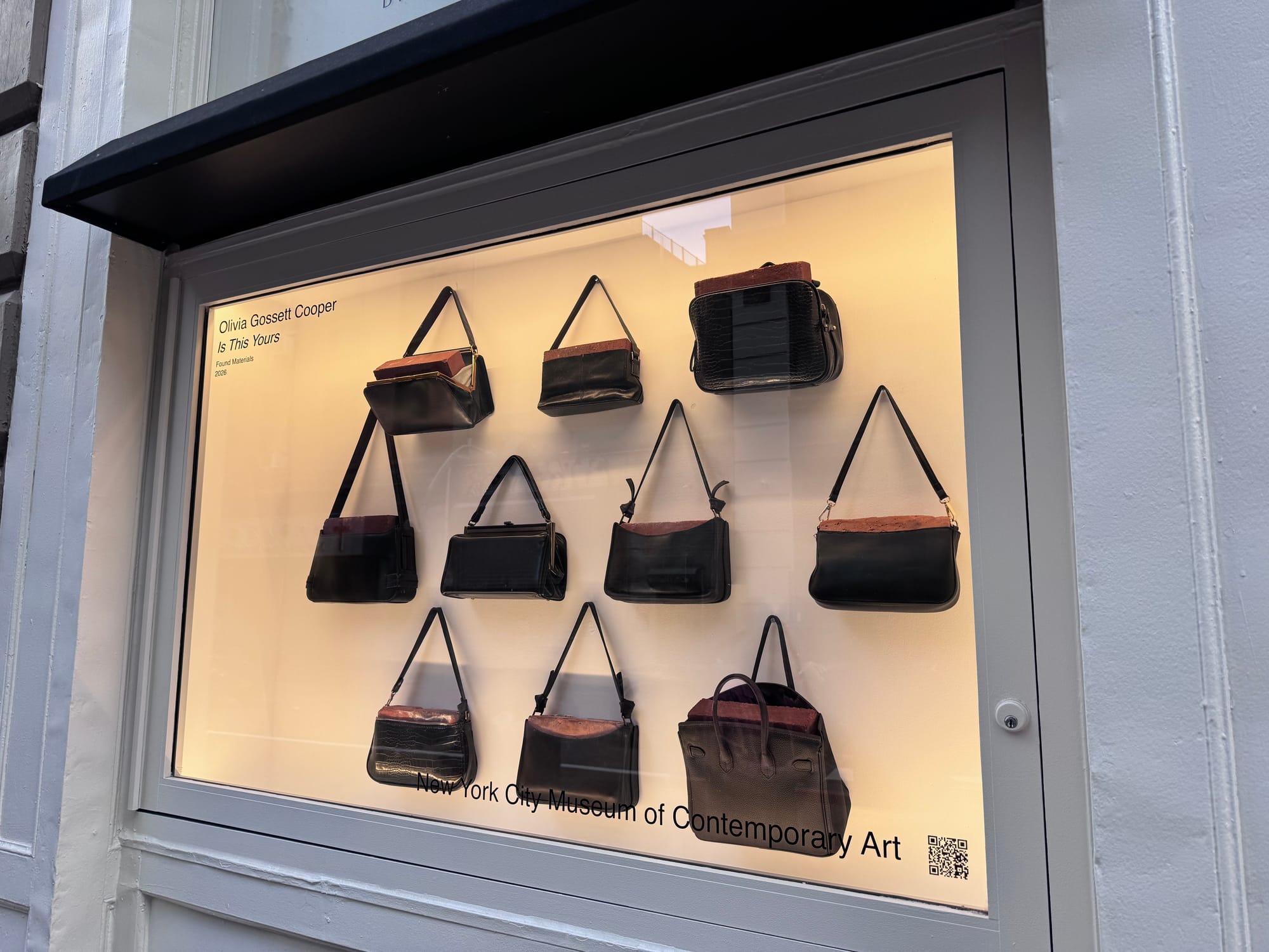 Ten black purses each with bricks are seen inside an illuminated window