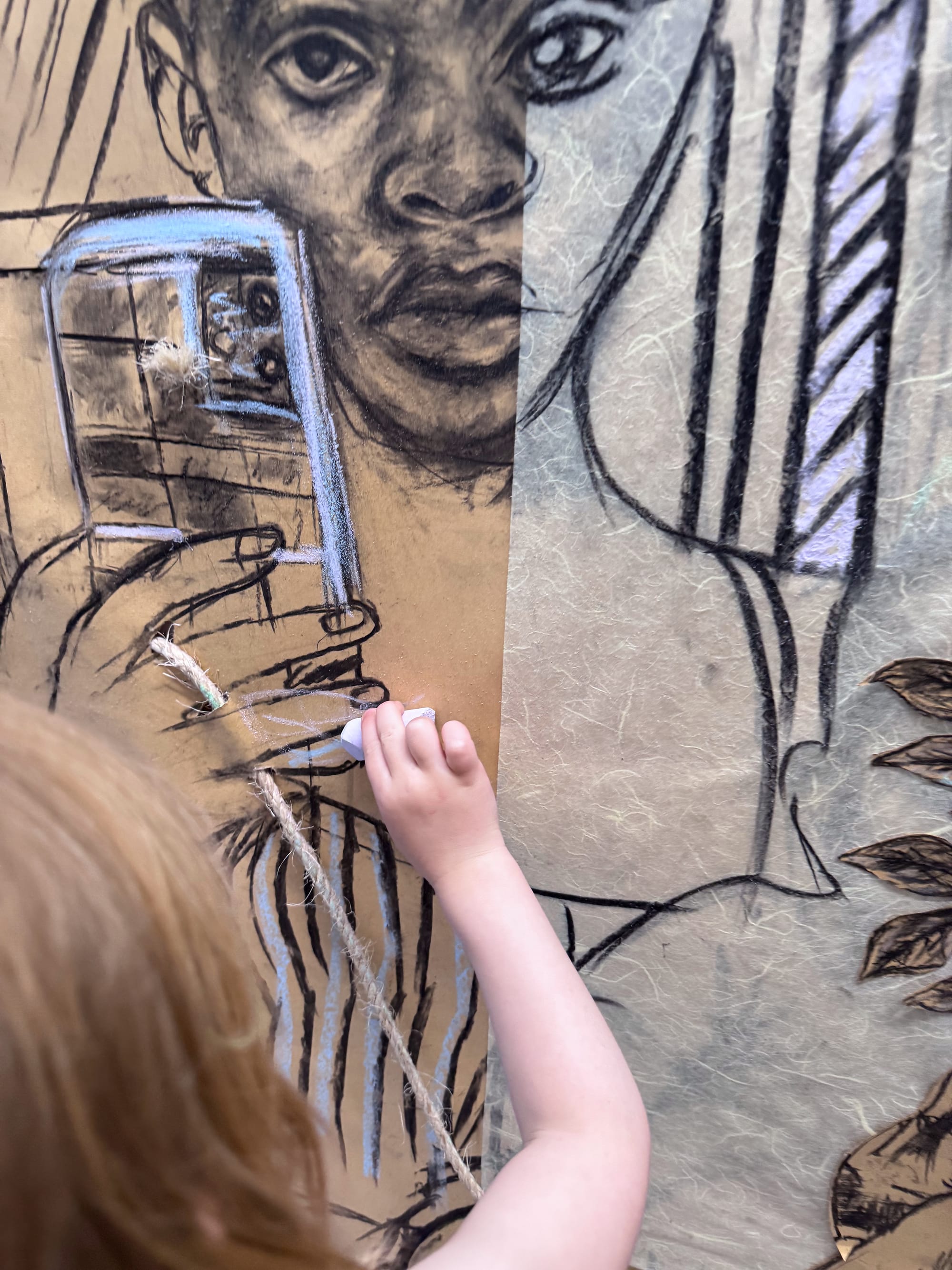 A young girl draw with chalk on an artwork by artist Lerato Ngobeni
