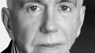 A black and white photo closely cropped to the face of a man who looks directly at the camera