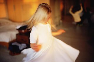 Blurred color photograph by Nan Goldin showing a young girl in a white dress twirling inside a softly lit bedroom