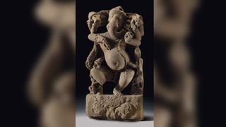 A sandstone sculpture of Ganesha is pictured against a black background