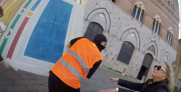 Students in high-visibility vests carry a replica of Simone Martini’s Guidoriccio da Fogliano as Mayor Nicoletta Fabio gestures in mock surprise during a staged prank.