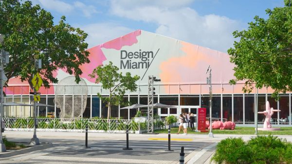 An external view of the Design Miami fair in 2023 as people walk past sculptures outside the tent.