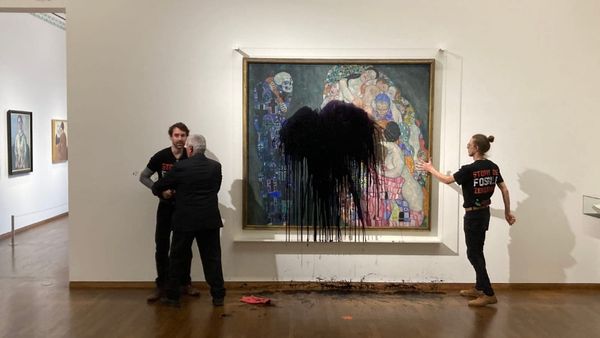 Authorities are seen detaining a protester who threw black paint onto a Gustav Klimt painting while the hand of another is pictured glued to the glass protecting it