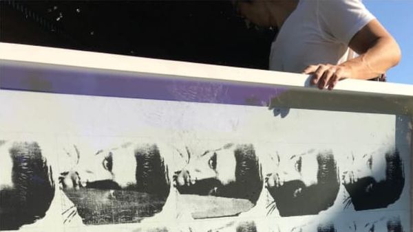 A man holds an artwork that was allegedly damaged in a fire at Ronald Perelman's home
