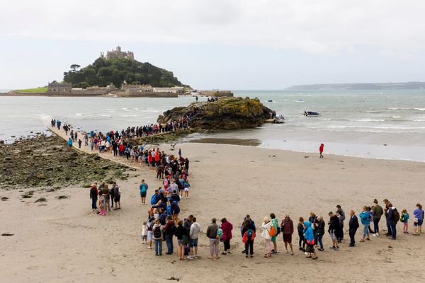 A photograph by Martin Parr depicting people lining up to cross the causeway to St. Michael’s Mount in Cornwall, England