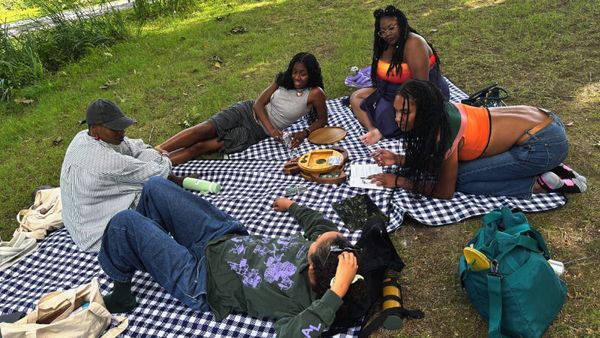 A group of people sit on picnic blankets playing a game