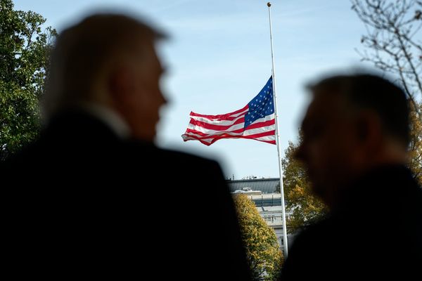 President Donald Trump speaks with Hungarian Prime Minister Viktor Orban outside of the Oval Office. They are out of focus with an American flag in focus in the background