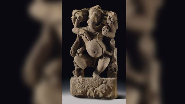 A sandstone sculpture of Ganesha is pictured against a black background