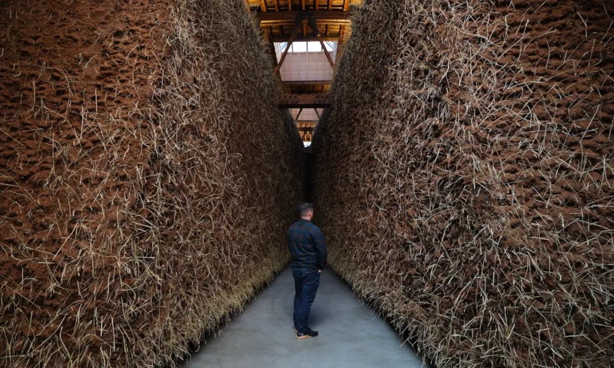 A man stands in between two giant earthen sculptures