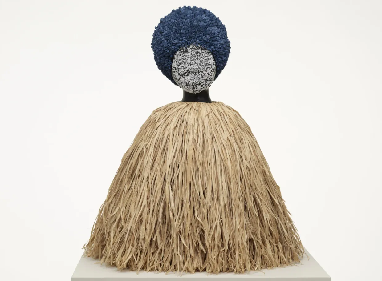 Art piece by Simon Leigh in which a sculpture resembling a woman with an afro is made out of materials.