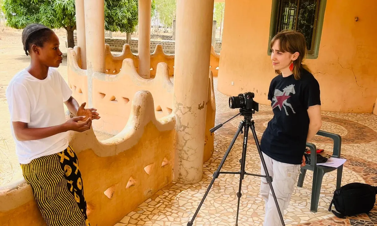 Flo, behind the camera, with an interviewee in Ghana