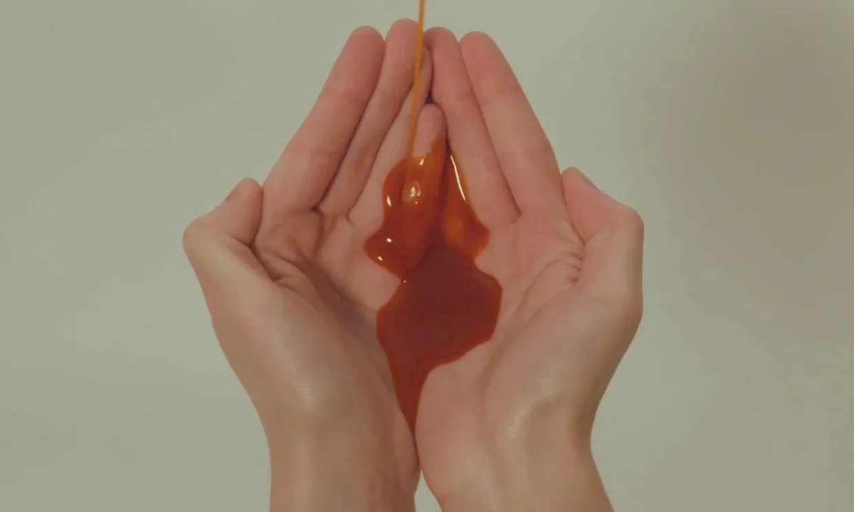 A close up shot of cupped hands, a red liquid resembling blood is pouring into them