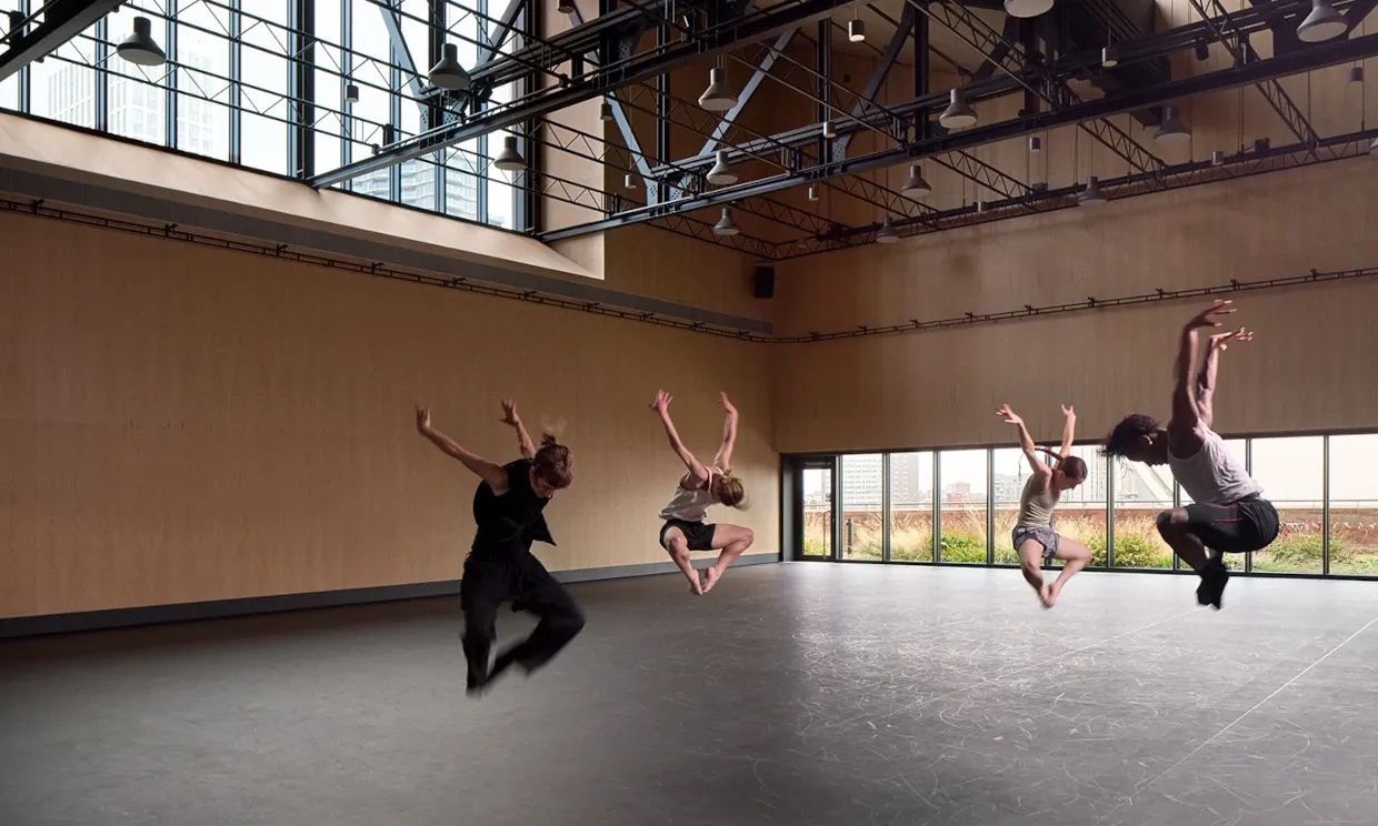 Four dancers jump in synchronisation inside a studio