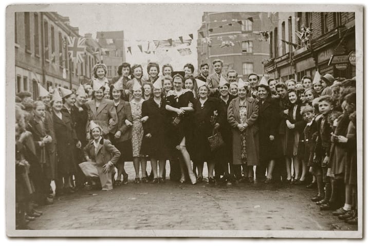 Harry Young, alias Diamond Lil, stands at the centre of photograph taken on VE Day 8 May 1945 on Columbia Road. From left kneeling; Gladys Herd, Mrs Stephens, Isabella Wilkinson, Clara Hoare, Nell Lloyd, Diamond Lil, Isabella Lloyd, Alice Wilkinson. Photograph: 