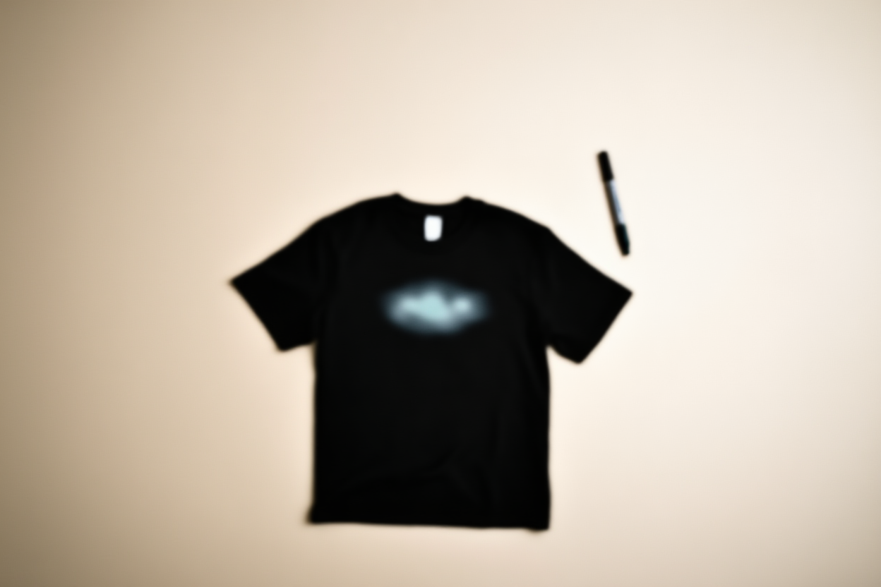 a t-shirt with a blurred logo on it next to a marker pen