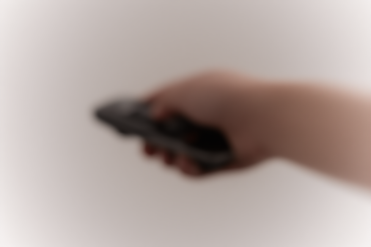 Un primer plano de una mano presionando un botón en un dispositivo control remoto elegante con desenfoque de fondo suave