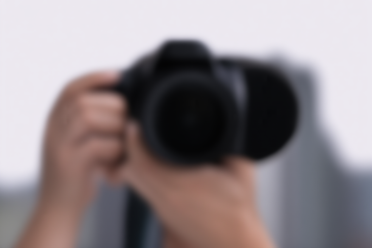 広角レンズを取り付けたプロフェッショナルな一眼レフカメラを持つ摄影师の手元のアップショット、前景で立っている