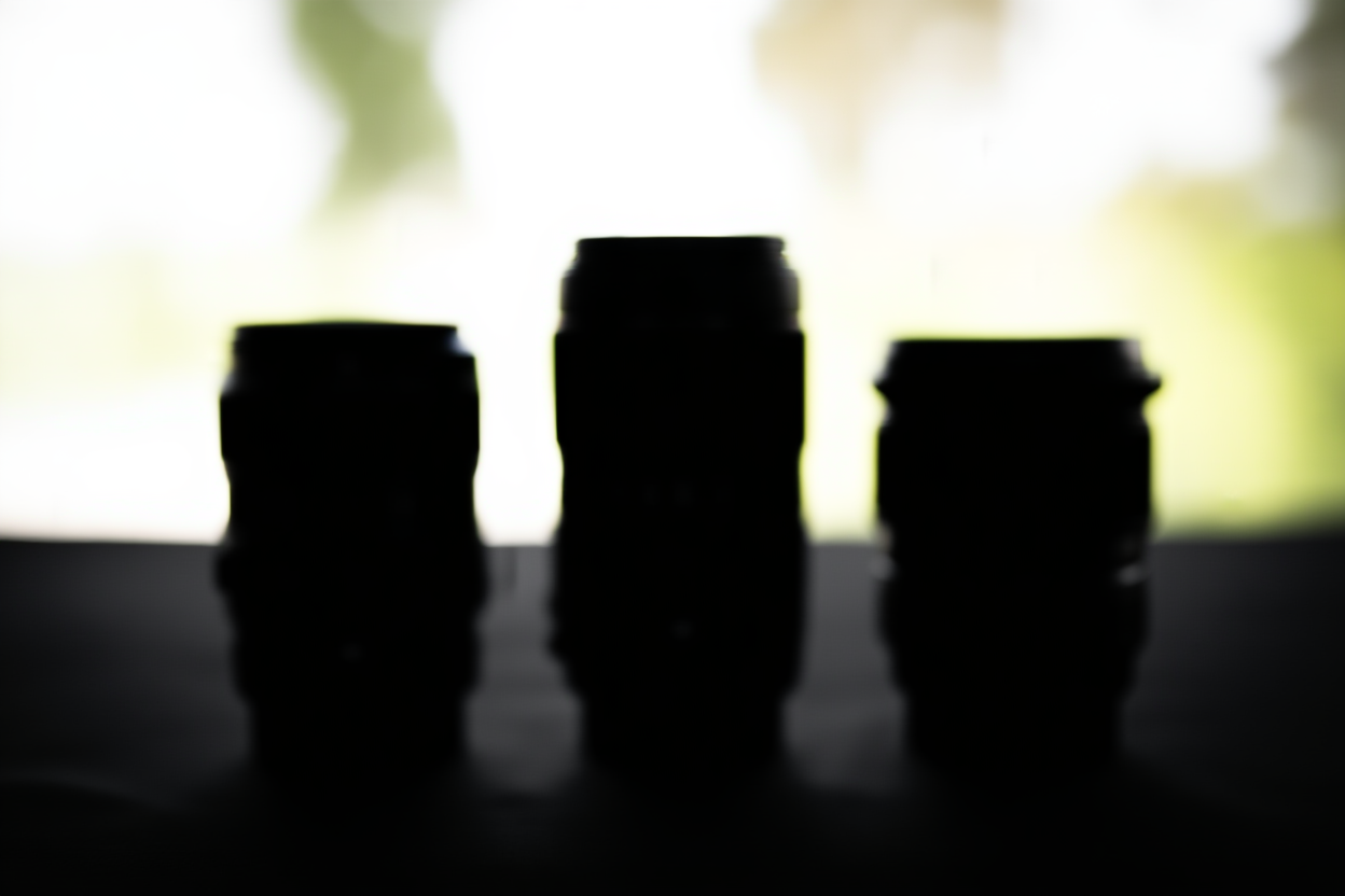 drei verschiedene Kameragehäuse in einer Reihe auf einer dunklen Oberfläche mit Bokeh-Hintergrund, weches Studiobeleuchtung, weitwinklig