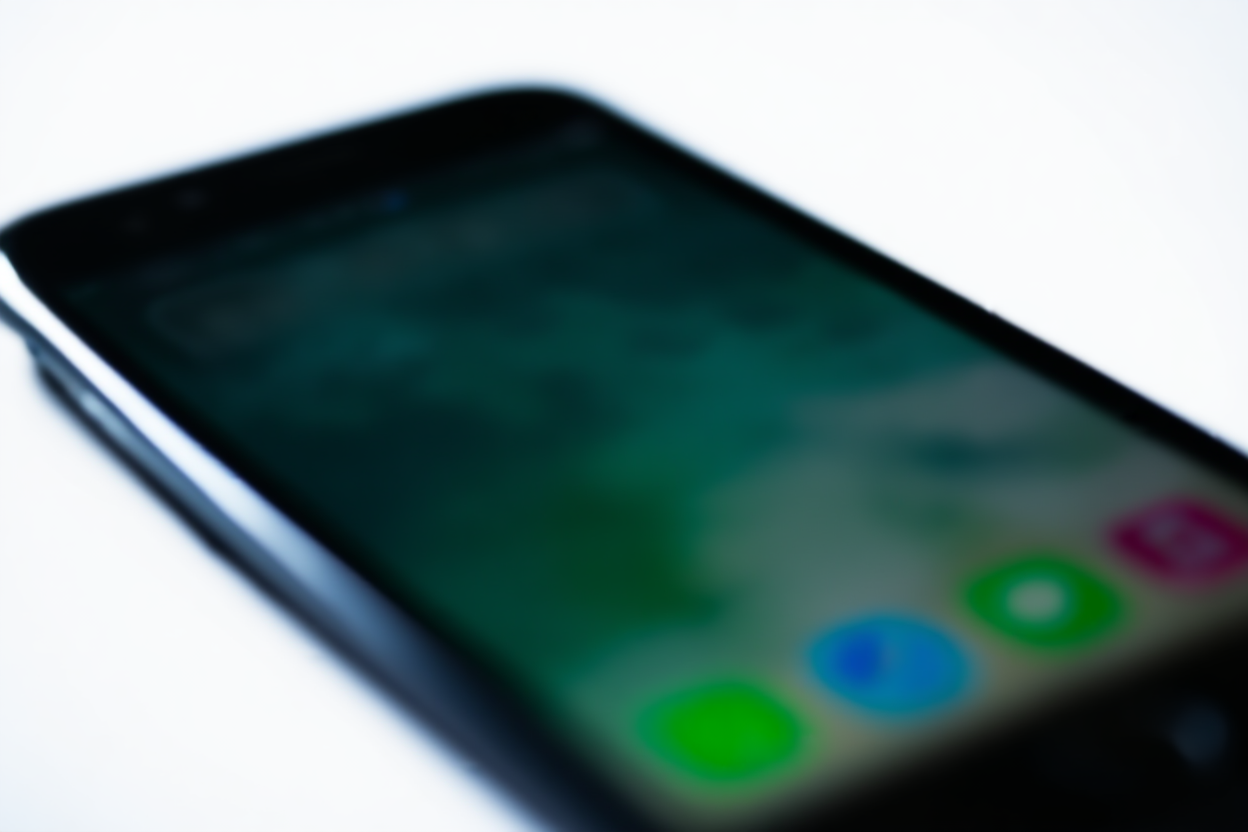 sebuah smartphone menampilkan ikon aplikasi berwarna-warni di layar terhadap latar belakang buram, cahaya siang lembut, bidikan lanskap lebar